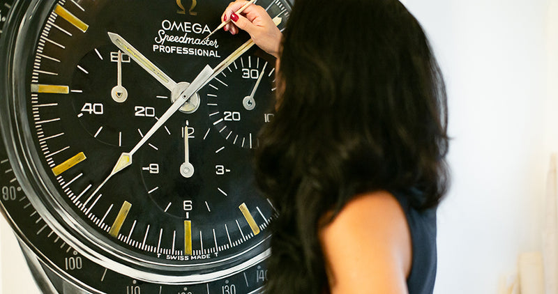 Cecilia Mendoza, known as CM Visual Artist, painting an Omega Speedmaster-inspired watch artwork detail.